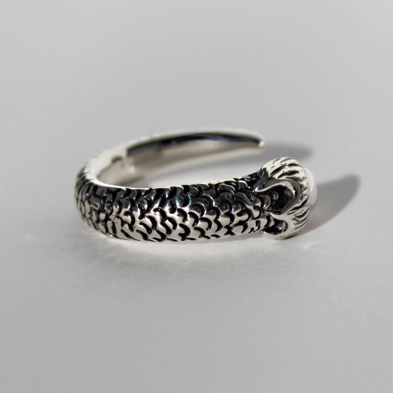 Puede incluir: Un anillo de plata con un dise&ntilde;o detallado de cabeza de serpiente en la banda.