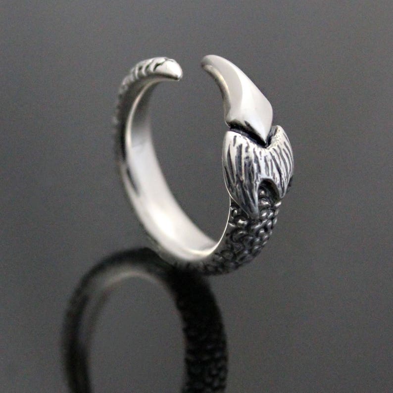 Puede incluir: Un anillo de plata con un dise&ntilde;o de garra detallado. El anillo est&aacute; abierto y tiene un acabado texturizado.