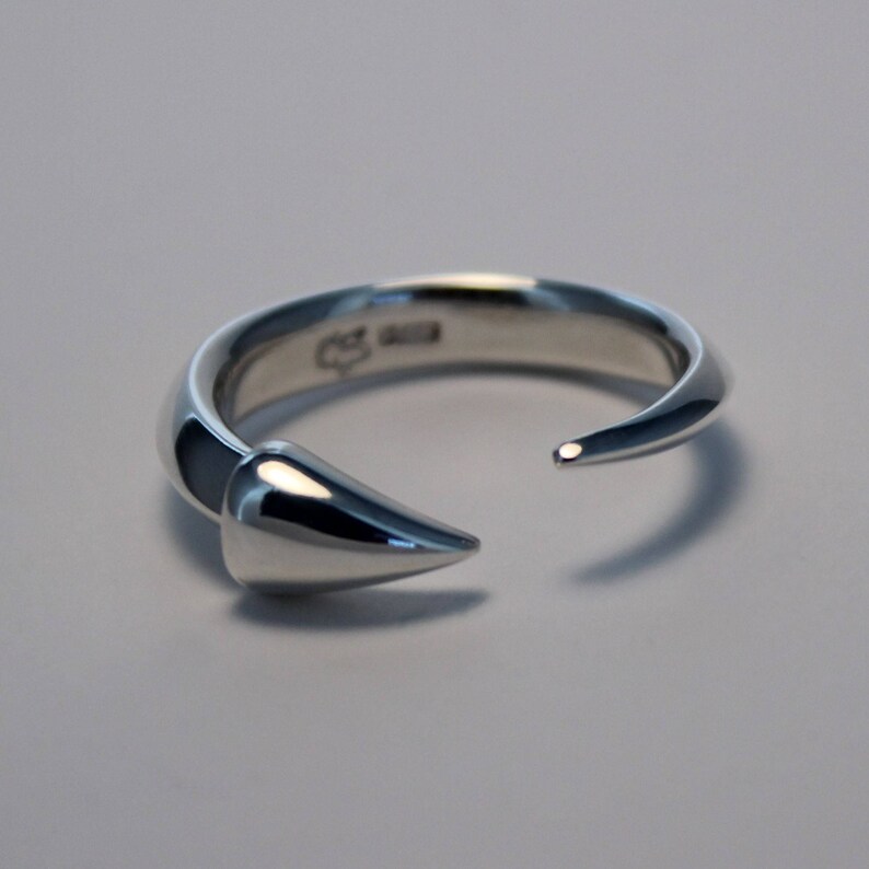 Puede incluir: Un anillo de plata con un dise&ntilde;o puntiagudo y curvo. El anillo est&aacute; abierto por un lado y tiene un acabado liso y pulido.