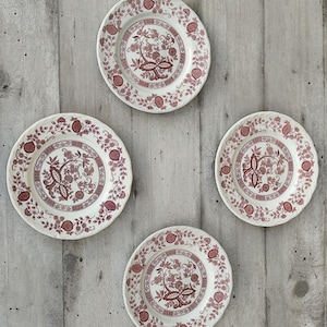 Peut inclure: Ensemble de quatre assiettes plates en céramique blanche avec un motif floral rouge. Les assiettes ont un bord surélevé et un bord festonné.