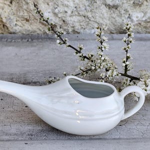 May include: A white ceramic mug with a black handle and the text "But First, Coffee" in a black, handwritten-style font. The mug is on a white surface.