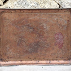 Puede incluir: Bandeja rectangular de cobre con un diseño grabado de dragones y motivos florales. La bandeja tiene un aspecto envejecido y deslustrado con un borde plateado. El diseño incluye caracteres chinos.