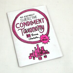 May include: A pink and white book cover with the title "An Entirely Subjective Condiment Taxonomy" by Emma Charleston. The cover also includes a pink star with the text "UK Based".