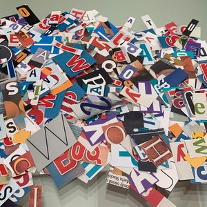 May include: A pile of colorful paper letters and numbers, cut from magazines and newspapers. The letters are in various fonts and sizes, and some are in bold or italics. The letters are arranged in a random order, and some are overlapping.