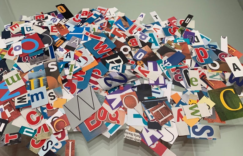 May include: A pile of colorful paper letters and numbers, cut from magazines and newspapers. The letters are in various fonts and sizes, and some are in bold or italics. The letters are arranged in a random order, and some are overlapping.