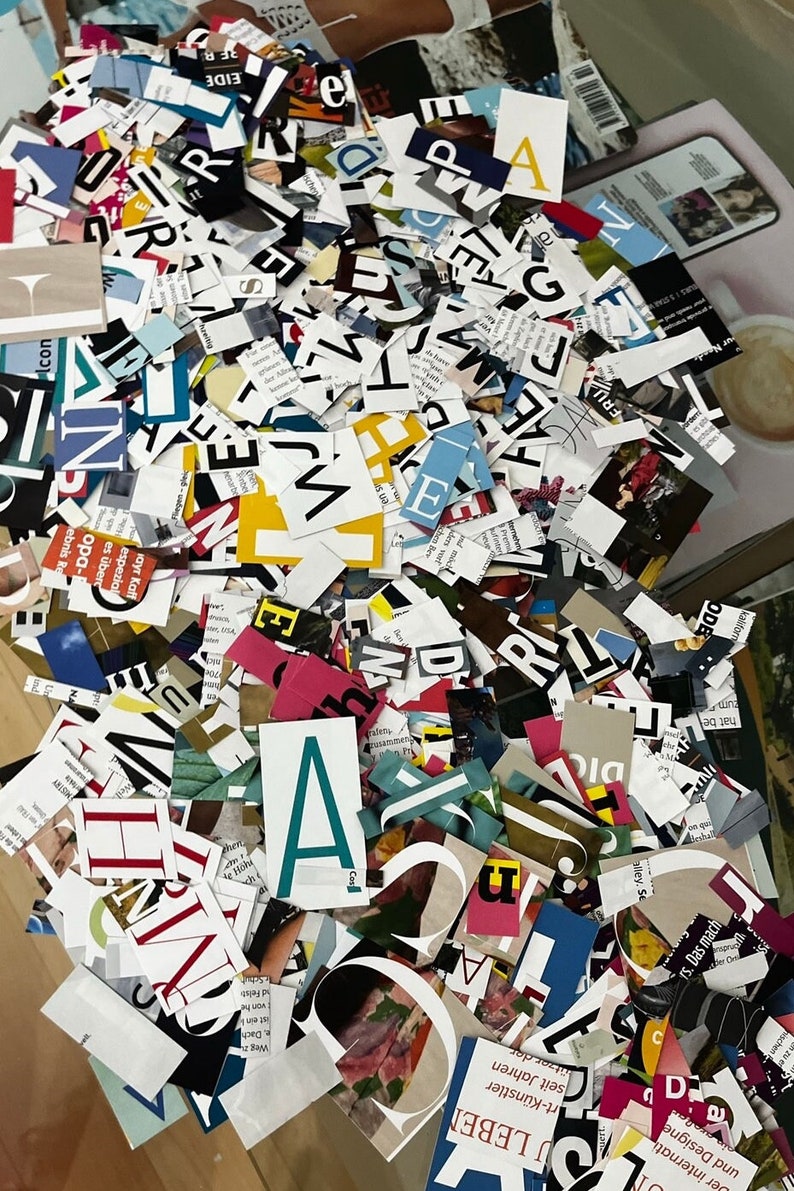 May include: A large pile of colorful, cut-out letters from magazines. The letters are in various fonts and sizes, and some are overlapping. The letters are mostly black, white, and red, but there are also some blue, green, and yellow letters.