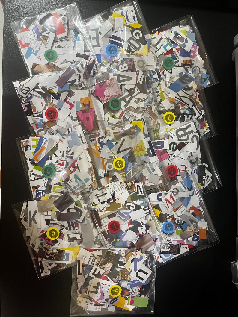 May include: Nine clear plastic bags filled with colorful paper scraps. The scraps are cut into various shapes and sizes, and some have letters printed on them. The bags are arranged in a pyramid shape on a black surface.