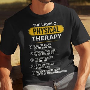 May include: Black t-shirt with the text "THE LAWS OF PHYSICAL THERAPY" in white and yellow. The shirt lists five rules of physical therapy, including "If you can walk in, you can work out."