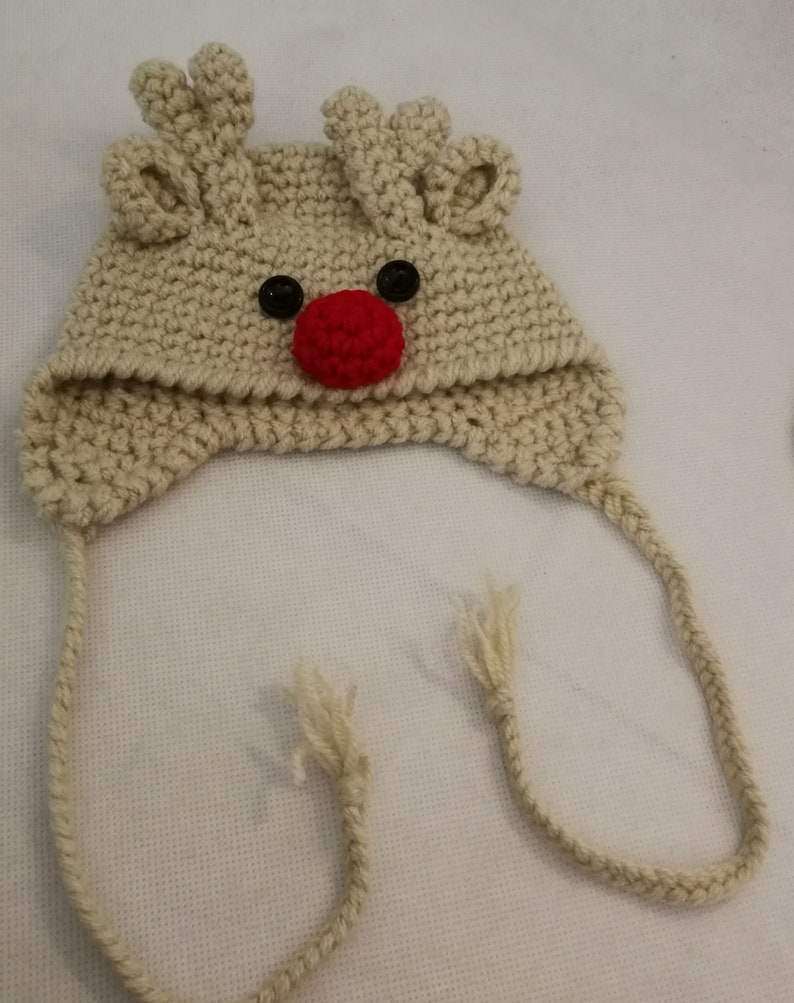 Together in wool cap and mittens baby reindeer and small dog carry by hand crochet