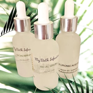 Pode incluir: Tr&ecirc;s frascos de vidro fosco de s&eacute;rum facial com conta-gotas brancos e colares prateados. Os frascos t&ecirc;m r&oacute;tulos que dizem "My Bath Infusions FACIAL SERUM". O fundo &eacute; verde suave com folhas de palmeira.