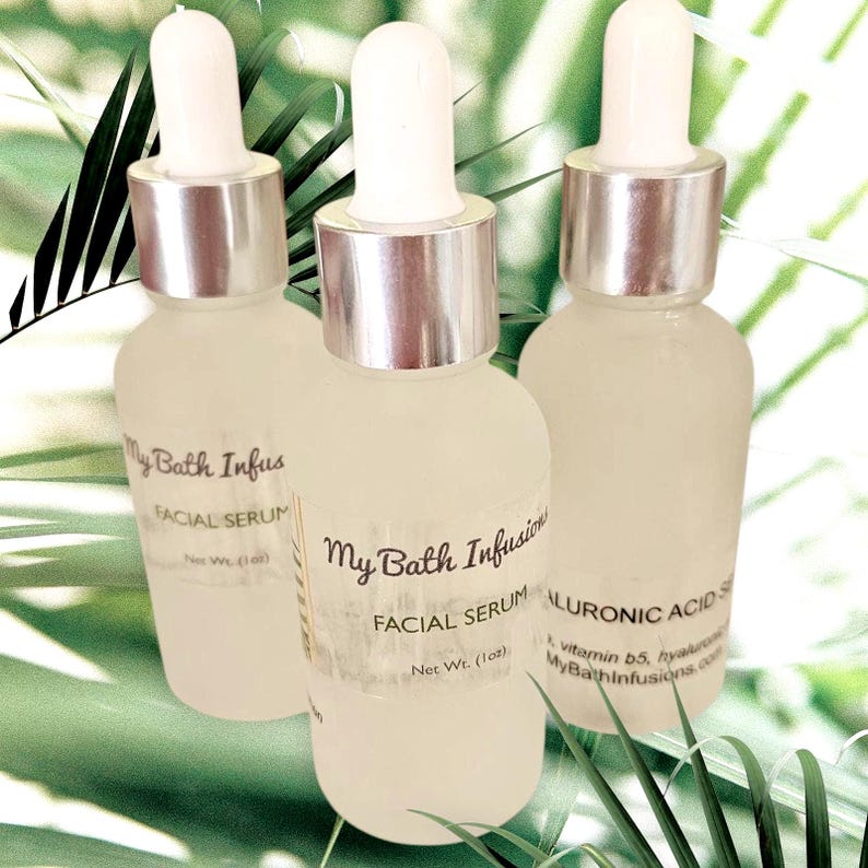 Pode incluir: Tr&ecirc;s frascos de vidro fosco de s&eacute;rum facial com conta-gotas brancos e colares prateados. Os frascos t&ecirc;m r&oacute;tulos que dizem "My Bath Infusions FACIAL SERUM". O fundo &eacute; verde suave com folhas de palmeira.