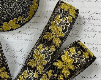Puede incluir: Borde negro y dorado con un diseño floral. El borde está hecho de una tela tejida con un acabado brillante.