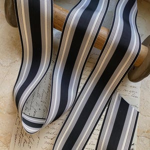 May include: Black and white striped ribbon with a satin finish. The ribbon is approximately 1 inch wide.