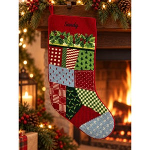 May include: A red needlepoint Christmas stocking featuring the name Sandy embroidered in black script. The stocking displays a patchwork design of various patterns including plaid, polka dots, and pine trees in red, green, blue, and white colors.