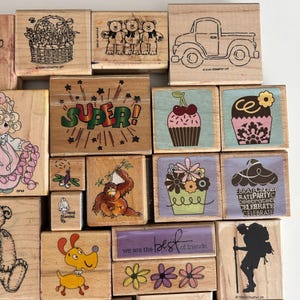 May include: A collection of wooden stamps with various designs. Images include a basket of flowers, three teddy bears, a truck, a cupcake with cherries, a cupcake with a flower, the word "SUPER!", a dragonfly, a monkey, a dog, and the text "we are the best of friends."