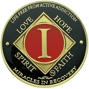 May include: Gold-colored coin with a black background and a red circle in the center. The circle has a gold-colored 'I' in the center. The coin has the words 'Life Free From Active Addiction' around the top edge, 'Love, Hope, Spirit, Faith' around the diamond shape, and 'Miracles in Recovery' around the bottom edge.