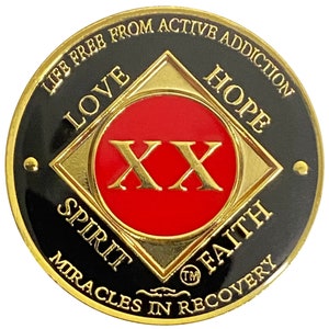 Puede incluir: Una moneda redonda dorada y negra con las palabras "Life Free From Active Addiction" alrededor del borde. El centro de la moneda tiene un círculo rojo con el número "XX" en letras doradas. Las palabras "Love", "Hope", "Spirit", "Faith", "Miracles in Recovery" y "TM" están alrededor del círculo rojo.