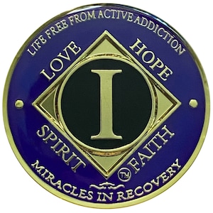 May include: A gold-colored coin with a purple background. The coin features a black diamond with a gold border and the letter "I" in gold inside. The words "Love", "Hope", "Spirit", and "Faith" are inscribed around the diamond. The words "Life Free From Active Addiction", "Miracles in Recovery", and "TM" are inscribed around the edge of the coin.