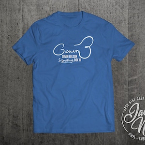 May include: A royal blue t-shirt with a white graphic of a signature and the text "Gaun G3 Gavin Belson Signature Box III". The bottom right corner of the image shows a white logo with the text "Jack Nine Creative Vinyl Embroidery Apparel".