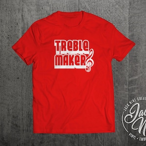 May include: Red t-shirt with white text that reads "Treble Maker" with a treble clef symbol. The shirt is a standard t-shirt style with short sleeves. The text is in a bold, blocky font.