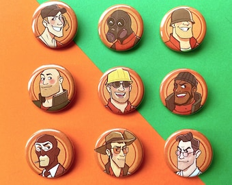 May include: Nine round button pins featuring cartoon characters from the video game Team Fortress 2. The pins are orange with black outlines and feature characters like the Scout, Demoman, Heavy, Engineer, Medic, Sniper, Pyro, and Soldier.