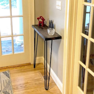 May include: A dark wood console table with black hairpin legs. The table is decorated with a red reindeer figurine and a glass bowl.