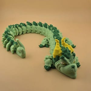 May include: A green and yellow dragon sculpture with a detailed, textured design. The dragon has a long, segmented body, with a head featuring large eyes and horns. The sculpture is made of a light green material with darker green and yellow accents.