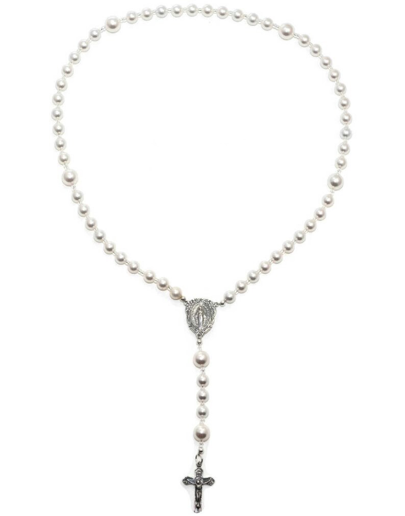 White pearl prayer beads on white background. Pearls are spaced by silver lined clear seed beads. It has a sterling silver Virgin Mary Rosary Center charm and Sterling Silver Crucifix pendant.