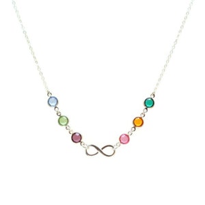 May include: A silver infinity necklace with colorful gemstones. The necklace features six round gemstones in shades of blue, green, pink, and orange.
