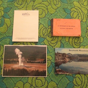 Op de afbeelding: Een verzameling vintage ansichtkaarten met schilderachtige uitzichten op Yellowstone National Park en de Beartooth Mountains. De ansichtkaarten bevinden zich op een groene achtergrond met een bloemenpatroon.