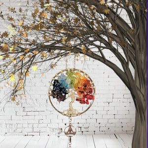 May include: A gold-colored metal wall hanging featuring a tree of life design. The tree's branches and roots are formed by a wire frame, with colorful gemstones representing the leaves. A small Buddha figure and a decorative ball hang below.