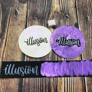 May include: A close-up of a purple and silver metallic ink pad with the word "illusion" written in silver on a white background, a purple background, and a black background.