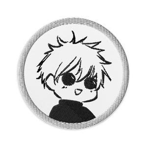 May include: Embroidered patch featuring a cartoon character with spiky white hair, large black eyes, and a black turtleneck. The patch is circular with a white background and a gray stitched border. The character has a small, open-mouthed smile.