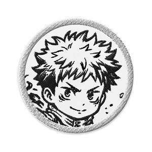 May include: A circular embroidered patch featuring a black and white line art illustration of a character with spiky hair and a determined expression. The design is rendered in black thread on a white background with a grey stitched border edge.