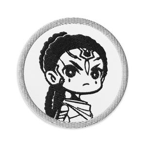 May include: Black and white embroidered patch of a cartoon woman with a serious expression. She has long black hair and is wearing a white outfit.