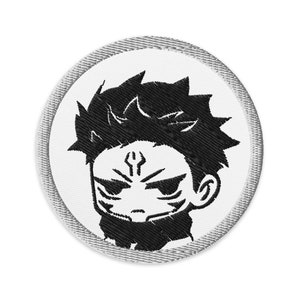 May include: Round, embroidered patch featuring a stylized black and white illustration of a character's face. The character has spiky hair and a determined expression. The patch has a white background and a gray border.