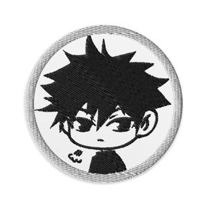 May include: Black and white embroidered patch of a cartoon character with spiky black hair, a serious expression, and a small cloud above their head.