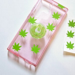 May include: A pink glitter phone case with a green leaf design and a pop socket with a green leaf design.