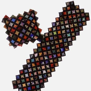 May include: A black and multi-coloured patchwork quilt runner with a heart-shaped cushion. The runner is made of squares with a rounded edge, and the cushion is made of the same fabric.