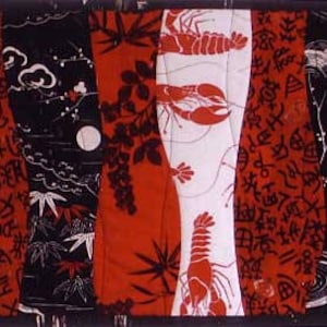 May include: A red, white and black fabric quilt with a repeating pattern of lobsters and Japanese characters. The quilt is made of different fabrics sewn together in a patchwork style.