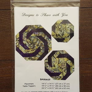 Könnte beinhalten: Ein Schnittmuster für spiralförmige Tischsets und Tischaufleger. Das Design zeigt drei achteckige Formen mit einem Paisley-Muster in Gold, Grün und Lila. Die Tischsets messen 37 cm x 37 cm. Der Text lautet 'Designs to Share with You'.