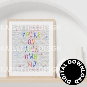 May include: A framed print with the text "YOU'RE ON YOUR OWN, KID" in colorful marker-style lettering. The background resembles lined paper. The print is in a light wood frame and is labeled "DIGITAL DOWNLOAD".