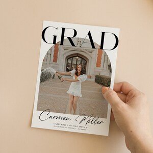 K&ouml;nnte beinhalten: Eine Graduation-Ank&uuml;ndigungskarte mit wei&szlig;em Hintergrund und schwarzem Text. Der Text lautet "GRAD" in gro&szlig;en Buchstaben oben auf der Karte. Ein Foto einer Frau in einem wei&szlig;en Kleid befindet sich in der Mitte der Karte. Das Foto ist kreisf&ouml;rmig. Der Text "Carmen Miller" befindet sich unter dem Foto, gefolgt von "University of Oklahoma" und "Bachelor of Science, Nursing".