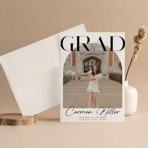 K&ouml;nnte beinhalten: Eine Graduation-Ank&uuml;ndigungskarte mit einem Schwarzwei&szlig;foto einer Frau in einem wei&szlig;en Kleid, die eine Champagnerflasche h&auml;lt. Der Text "GRAD" steht in gro&szlig;en schwarzen Buchstaben oben auf der Karte. Der Text "Carmen Miller" steht in kursiver Schrift unter dem Foto. Der Text "University of Oklahoma" und "Bachelor of Science - Nursing" steht in schwarzem Text unter dem Namen.