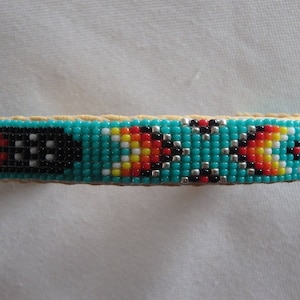 May include: A turquoise, black, white, red, and yellow beaded bracelet with a geometric pattern.