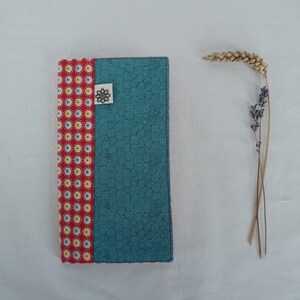 Peut inclure: Une couverture de carnet en tissu bleu et rouge avec un motif de tourbillon sur le côté bleu et un motif de pois rouge et blanc sur le côté rouge.