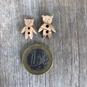 Peut inclure: Deux boutons en bois en forme d'ours avec deux trous chacun. Les boutons sont &agrave; peu pr&egrave;s de la taille d'une pi&egrave;ce d'un euro.