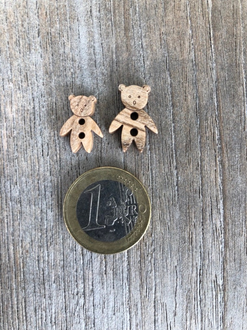 Peut inclure: Deux boutons en bois en forme d'ours avec deux trous chacun. Les boutons sont &agrave; peu pr&egrave;s de la taille d'une pi&egrave;ce d'un euro.