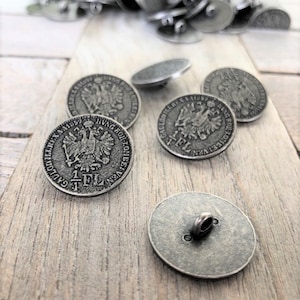 May include: A group of silver-toned metal buttons with a raised design of an eagle and the text "1 FL" on the front. The buttons have a loop on the back for sewing.