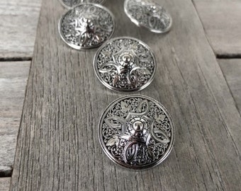 May include: Five silver metal buttons with intricate floral designs. The buttons have a raised center and a domed shape.